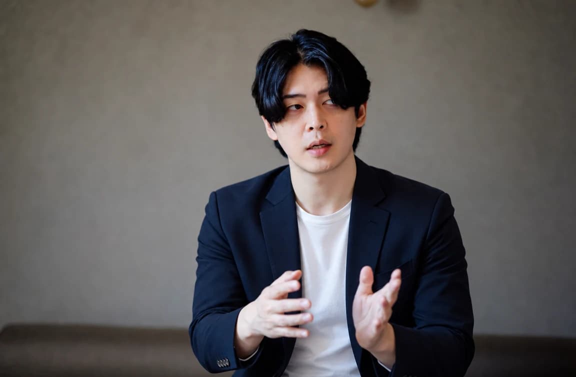ジャケット姿で、両手を動かしながら説明する代表の小坂井
